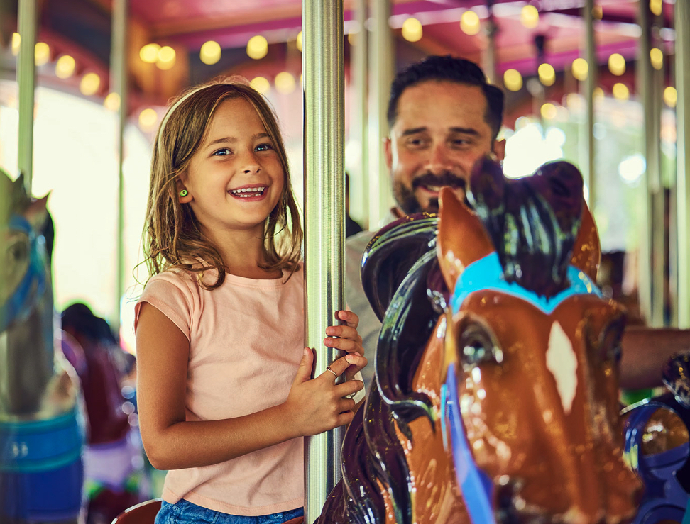A child enjoying the carousel with her father at the Carowinds Amusement Park
